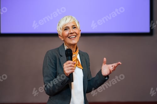 Preview: Portrait of a beautiful senior woman, holding a microphone, giving a speech.
