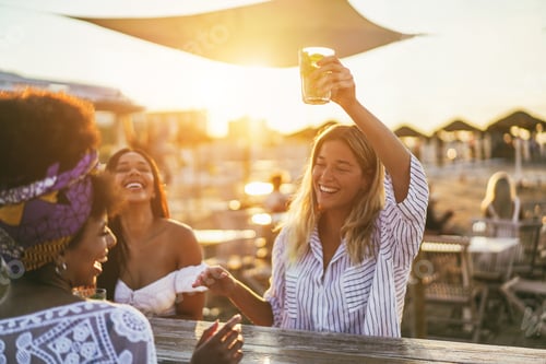 Preview: Happy girls having fun drinking cocktails at bar on the beach - Soft focus on african girl face