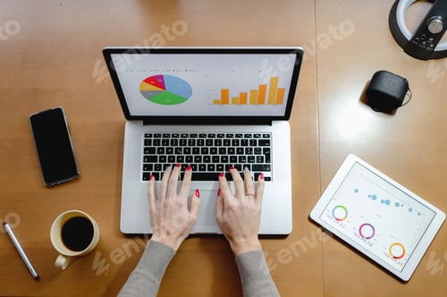 Preview: Top view of a businesswoman working on business charts on her laptop and tablet in the office