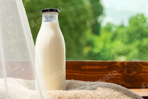 Preview: Bottle of milk against the background of green foliage