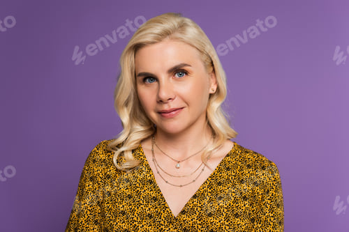 Preview: happy and blonde woman in blouse looking at camera isolated on purple