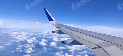 Preview: Airliner wing in a blue sky dotted with cotton clouds