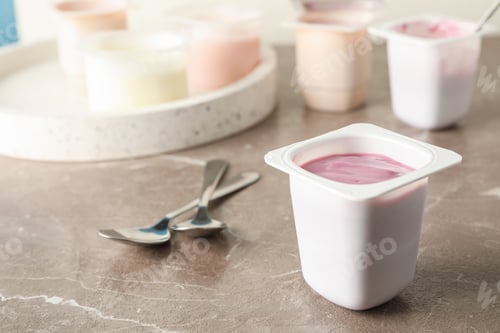 Preview: Composition with plastic cups with yogurt on grey table, space for text