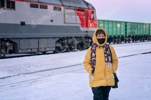 Preview: an elderly woman in a protective mask stands near the train on the platform