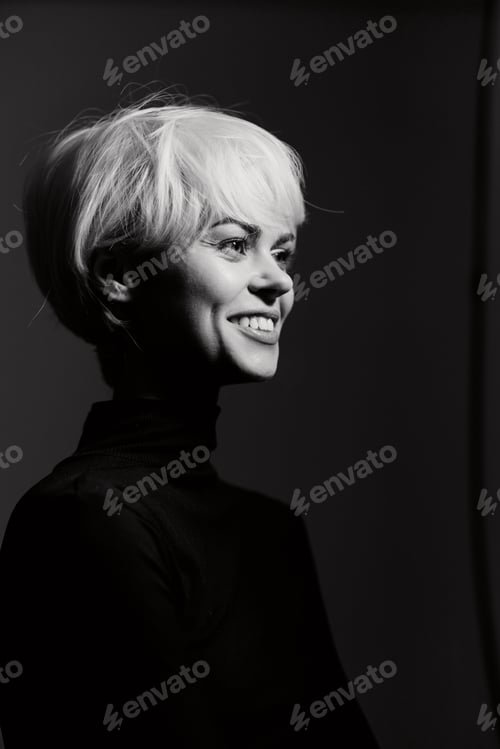 Preview: Smiling woman with short blonde hair wearing a black turtleneck, captured in a monochrome portrait