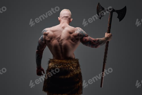 Preview: Tattooed viking with steel axe his back facing to camera