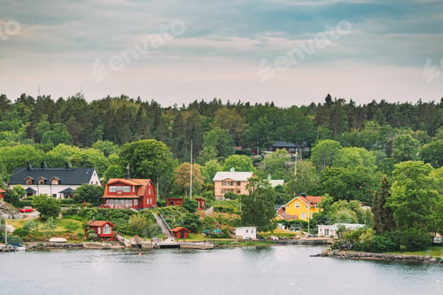 Preview: Sweden. Beautiful Red And Yellow Swedish Wooden Log Cabins Houses On Rocky Island Coast In Summer