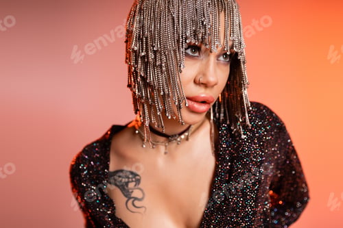 Preview: portrait of passionate tattooed woman in metallic headwear with shiny rhinestones looking away on