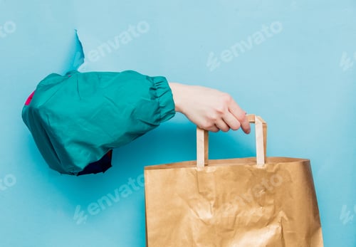 Preview: Female hand in 90s style jacket holding shopping bag