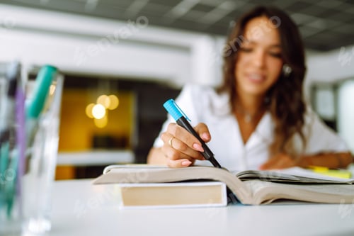 Preview: Female hand holding highlighter pen, highlighting marking important texts in study sheets.