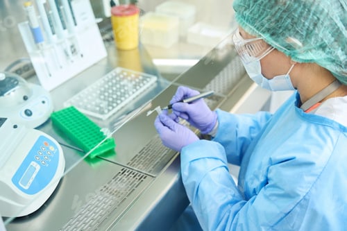 Preview: Woman in overalls and protective gloves marks test tubes with biomaterial