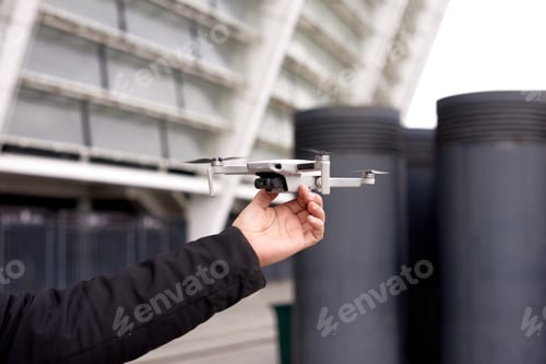 Preview: man hand hold drone before launch in city street. exploring new building with innovative technology