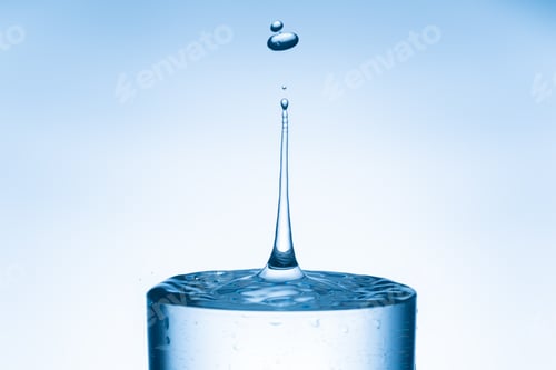 Preview: Water drop splashing into glass from isolated bright blue background