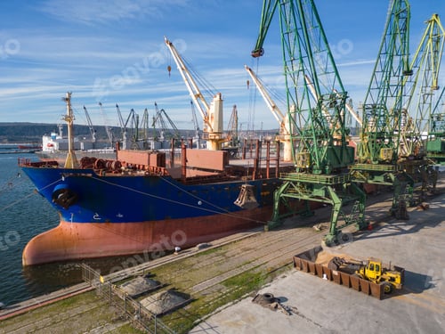 Preview: A bulk carrier ship loaded with grain is docked at a busy port, with workers and machinery seen in
