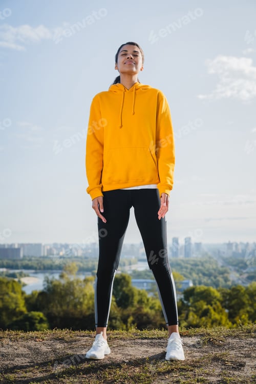 Preview: Vertical full length portrait of slim Afro female athlete in sporty outfit