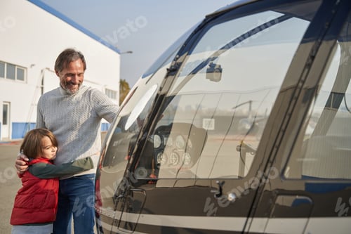 Preview: Joyful dad hugging his son near a helicopter