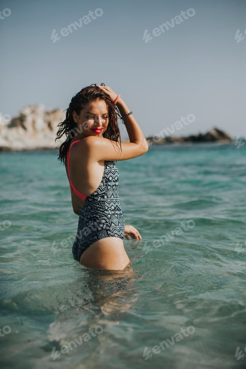 Preview: Young woman walking in the warm sea water at summer
