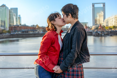 Preview: Young LGBT couple of women holding hands and sharing a kiss