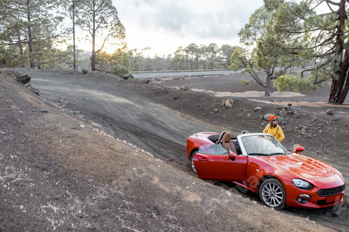 Preview: Woman with red cabriolet on the volcanic road