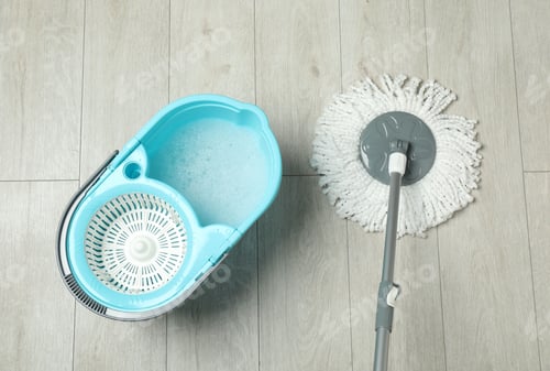Preview: String mop and bucket with detergent on wooden floor, top view