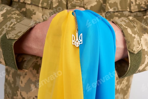 Preview: Ukrainian man warrior dressed in a military pixel uniform holds the yellow-blue flag