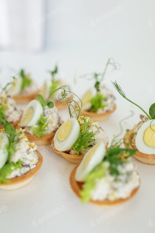 Preview: Close-up of tartlet with quail egg, cheese and chicken and microgreens. Food delivery and catering