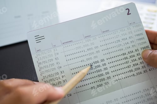 Dedo sosteniendo lápiz Datos puntuales Cantidad de retirada numérica en el libro de contabilidad bancaria