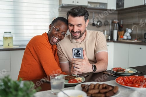 Preview: Happy multi-ethnic couple taking a selfie while having lunch in the kitchen