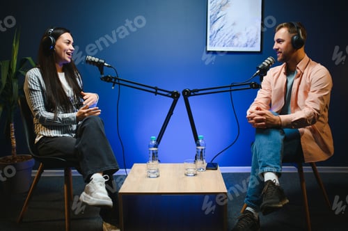 Preview: Female podcaster in headphones interviewing man guest using microphone, smiling,