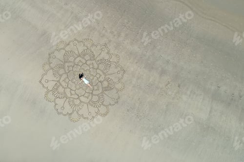 Preview: a large mandala painted on the sand on the ocean with a girl in the middle boho style.