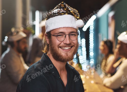 Preview: Portrait of a cheerful young man wearing a festive hat at home during christmas time