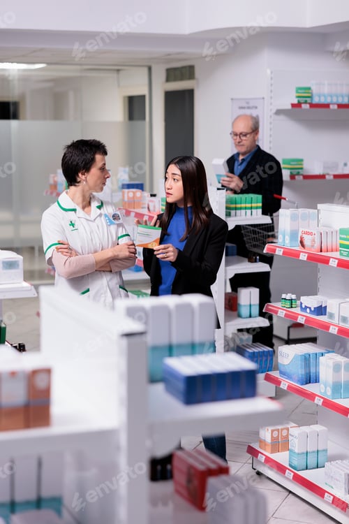 Preview: Pharmacy employee helping woman choosing vitamin c capsules