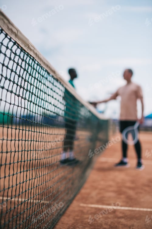 Preview: selective focus of friends shaking hands after playing tennis on court