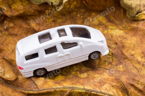 Preview: Closeup view of a white toy van with sunroofs on a brown surface
