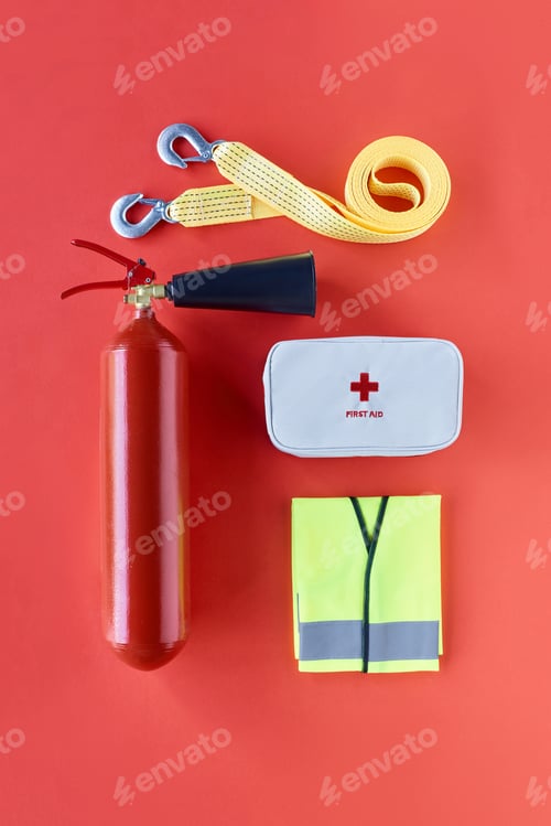 Preview: top view of fire extinguisher, car tow rope, reflective vest and first aid kit on red backdrop