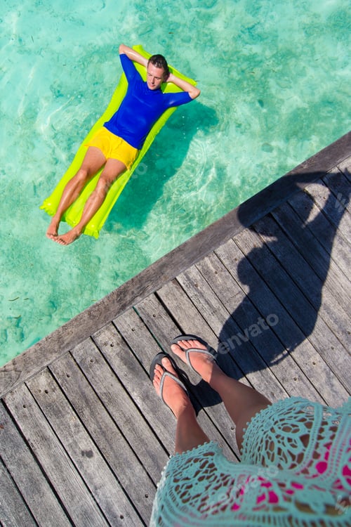 Preview: Young happy man relaxing on inflatable mattress in the sea