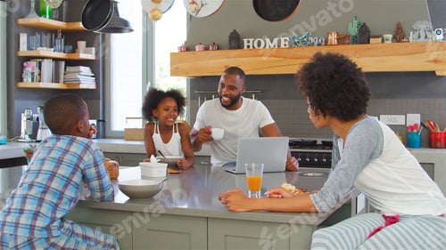 Preview: Family Wearing Pyjamas Sitting In Kitchen Enjoying Morning Breakfast Together