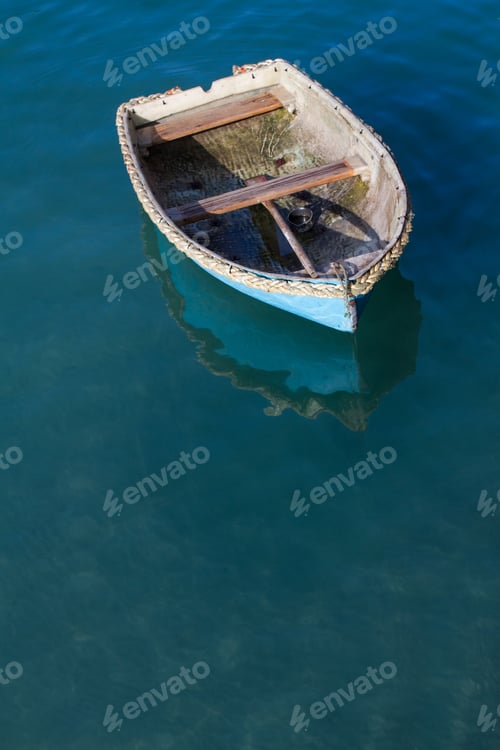 Vorschau: Ein kleines, verlassenes Ruderboot, das auf einem ruhigen Meer der Ruhe von seinen Liegeplätzen wegschwimmt
