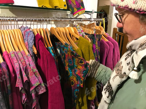 Preview: Woman looking at fashionable winter clothes in a boutique.