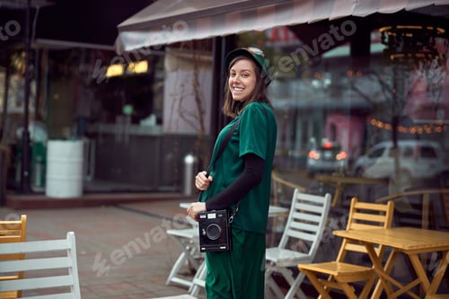 Preview: Happy young caucasian lady in green dress is walking near cozy cafe