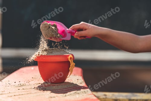 Preview: a girl makes a tower of sand from a bucket otdoors