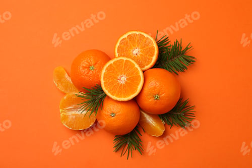 Preview: Ripe mandarins and pine branches on orange background, top view
