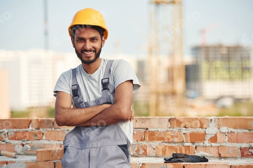 Preview: Standing with arms crossed. Handsome Indian man is on the construction site