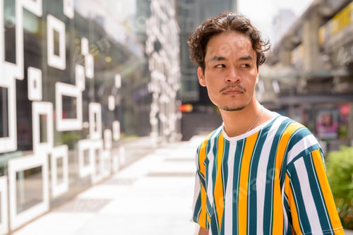 Preview: Portrait of handsome multi-ethnic young man wearing colorful shirt outdoors during summer in city