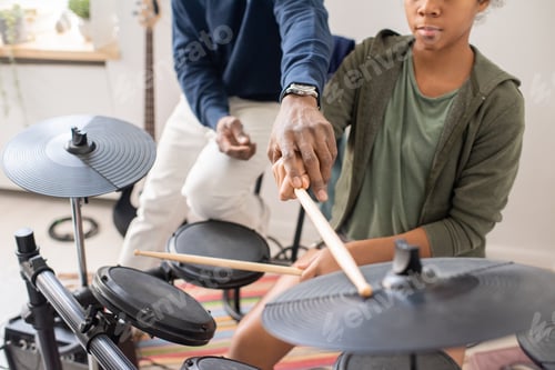 Preview: African male teacher explaining schoolgirl how to play drumkit