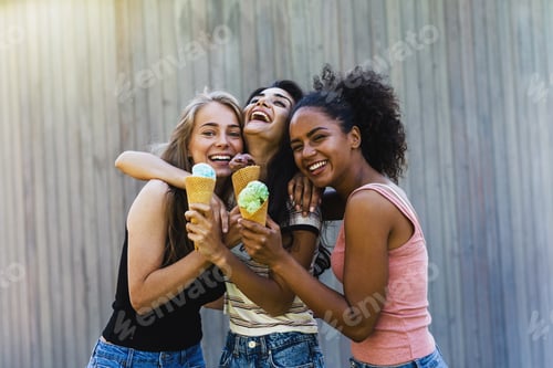 Preview: Three laughing girl friends with ice cream standing outdoors together