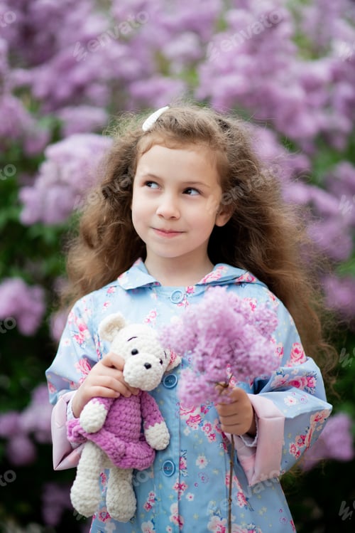 Preview: A cute girl next to a bush of blooming lilacs.