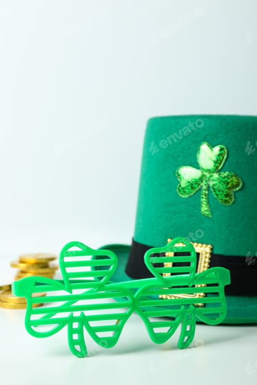 Preview: Top hat, chocolate coins and clover leaf glasses on white table