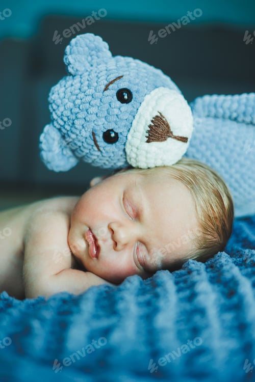 Preview: A newborn baby sleeps with a knitted teddy bear. Children's knitted toys. Baby sleep