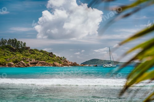 Preview: Blue shallow lagoon, white ocean wave and lonely yacht boat at Anse Cocos beach, La Digue island